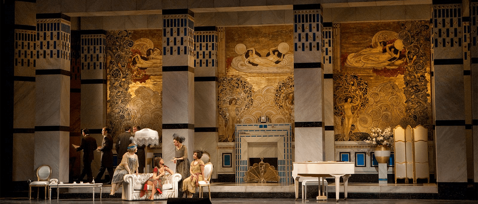 A stage with people sitting on couches and a fireplace.